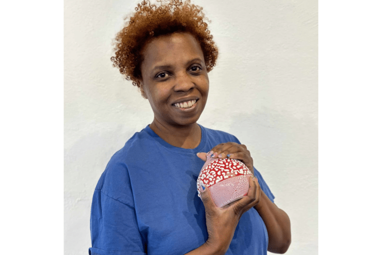 Christine Roth a sculpture instructor, holding a hand-painted ceramic vase.