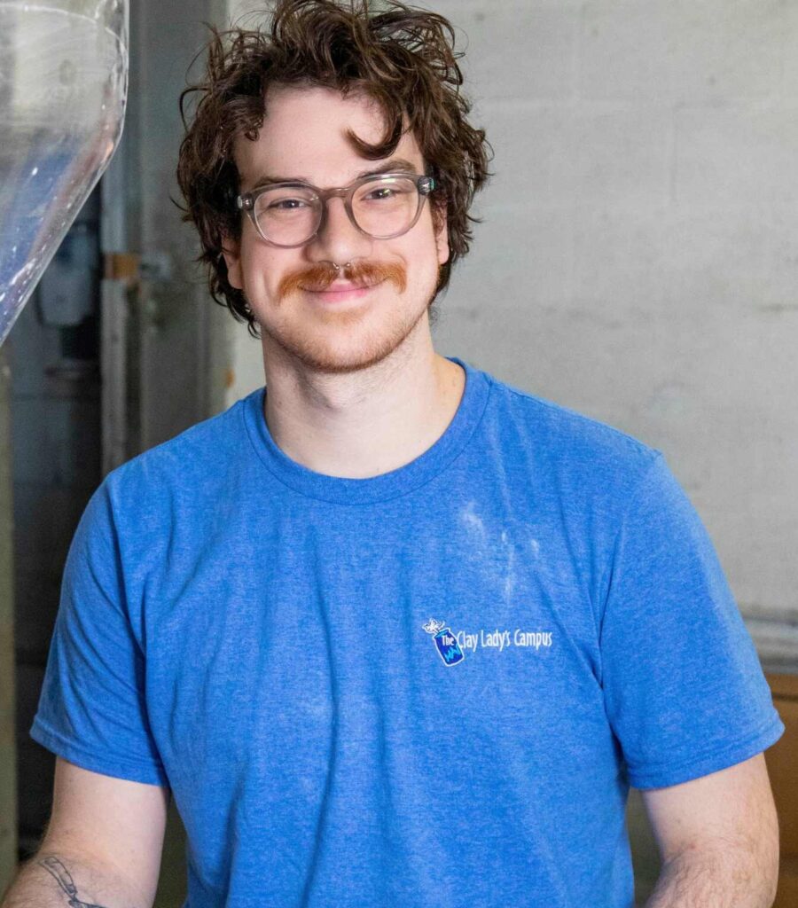 Henry Sekeres. the production manager at The Clady Lady in warehouse setting wearing a blue Clay Lady shirt.